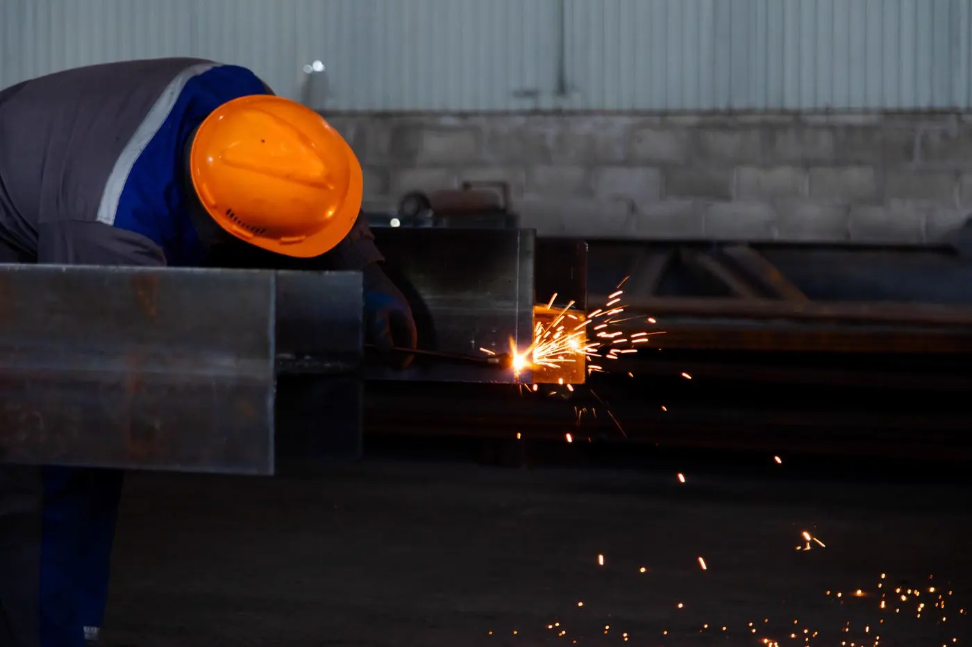 Kıvılcımlar arasında metal kesimi yapan operatör